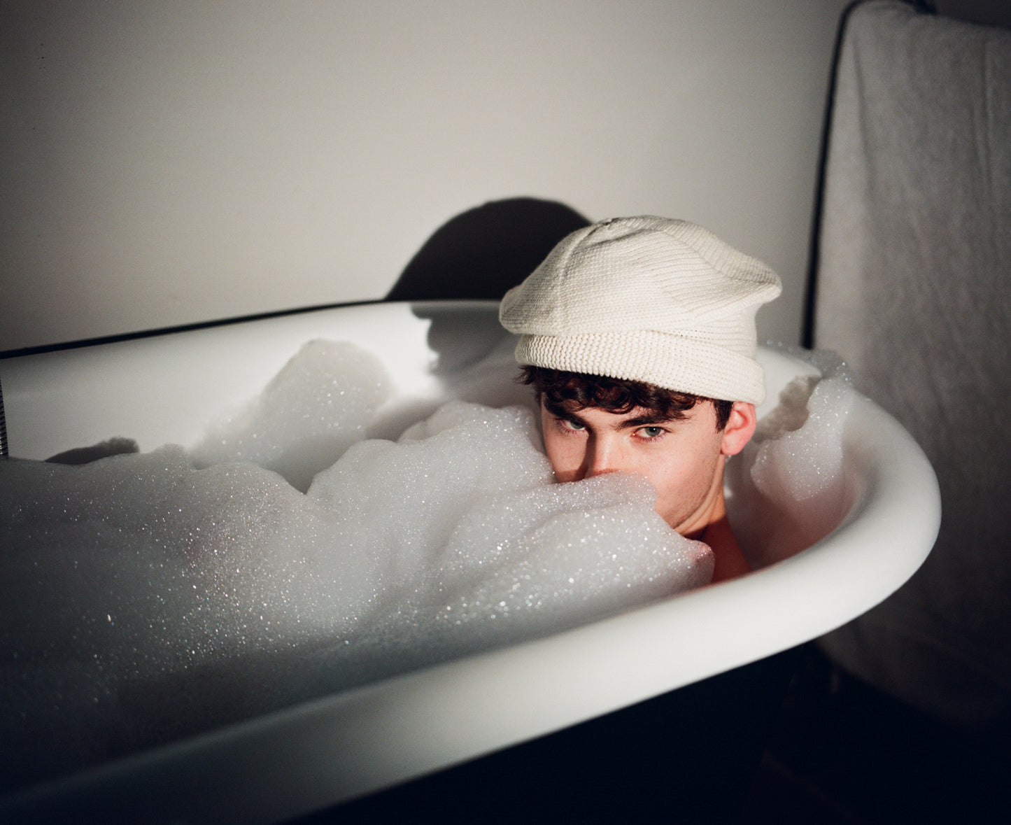 Model inside bathtub wearing sack hat in ecru