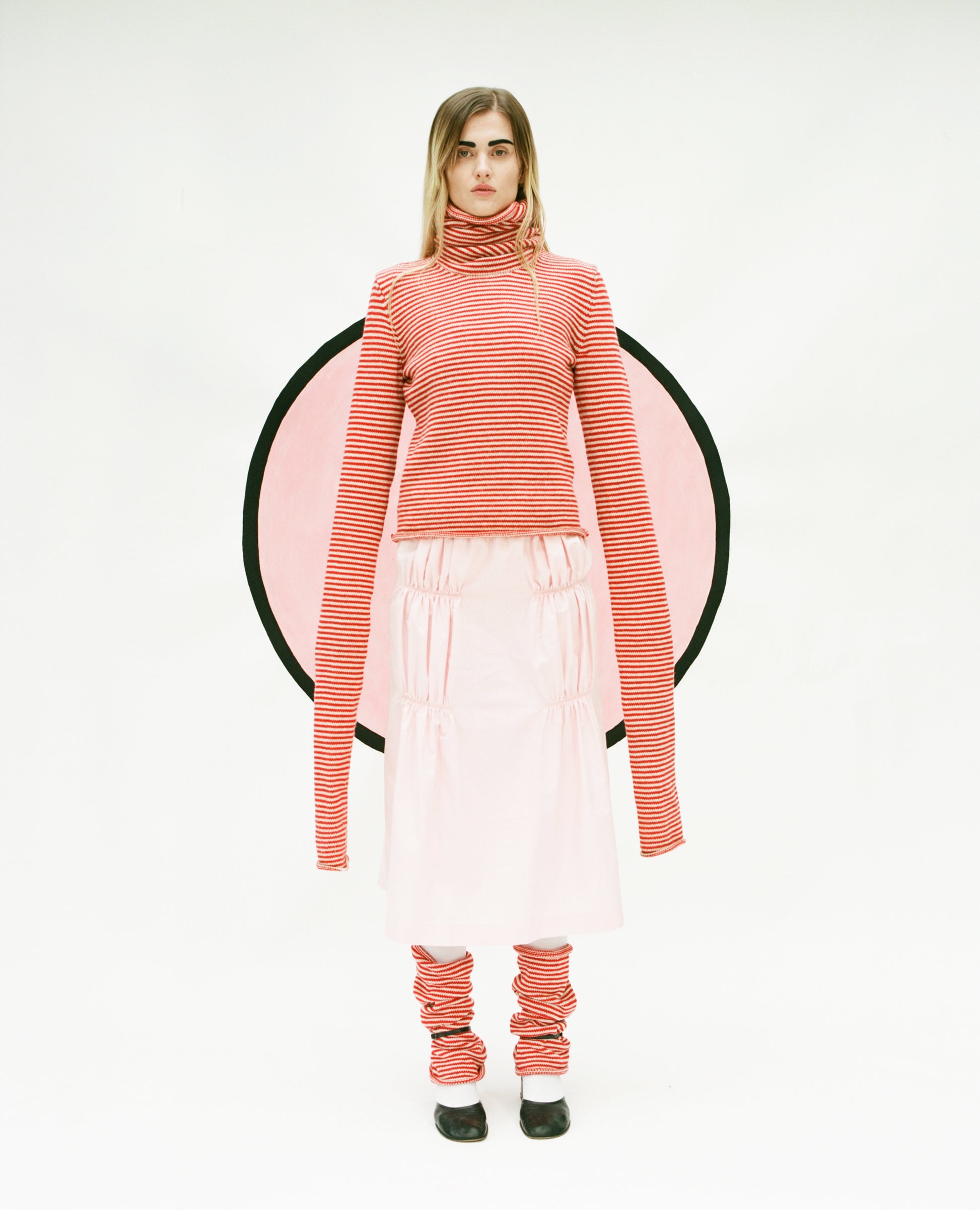 Model wearing stripy Double Snood top in red & oatmeal, Ruche cotton skirt in pink and stripy snood leg warmers also in red & oatmeal