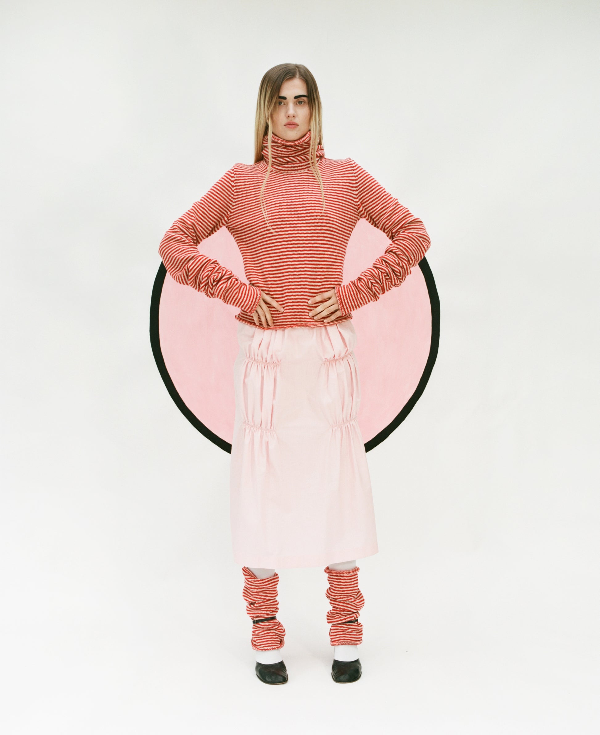 Model wearing stripy Double Snood top in red & oatmeal, Ruche cotton skirt in pink and stripy snood leg warmers also in red & oatmeal