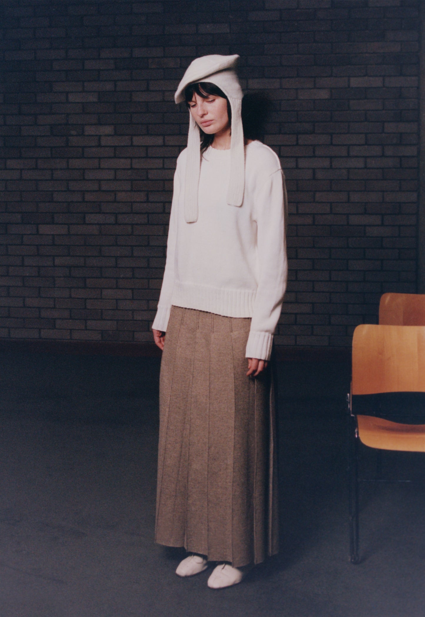 Model wearing Oatmeal Ankle Pleat Skirt with traditional sweater and classic hat in ecru