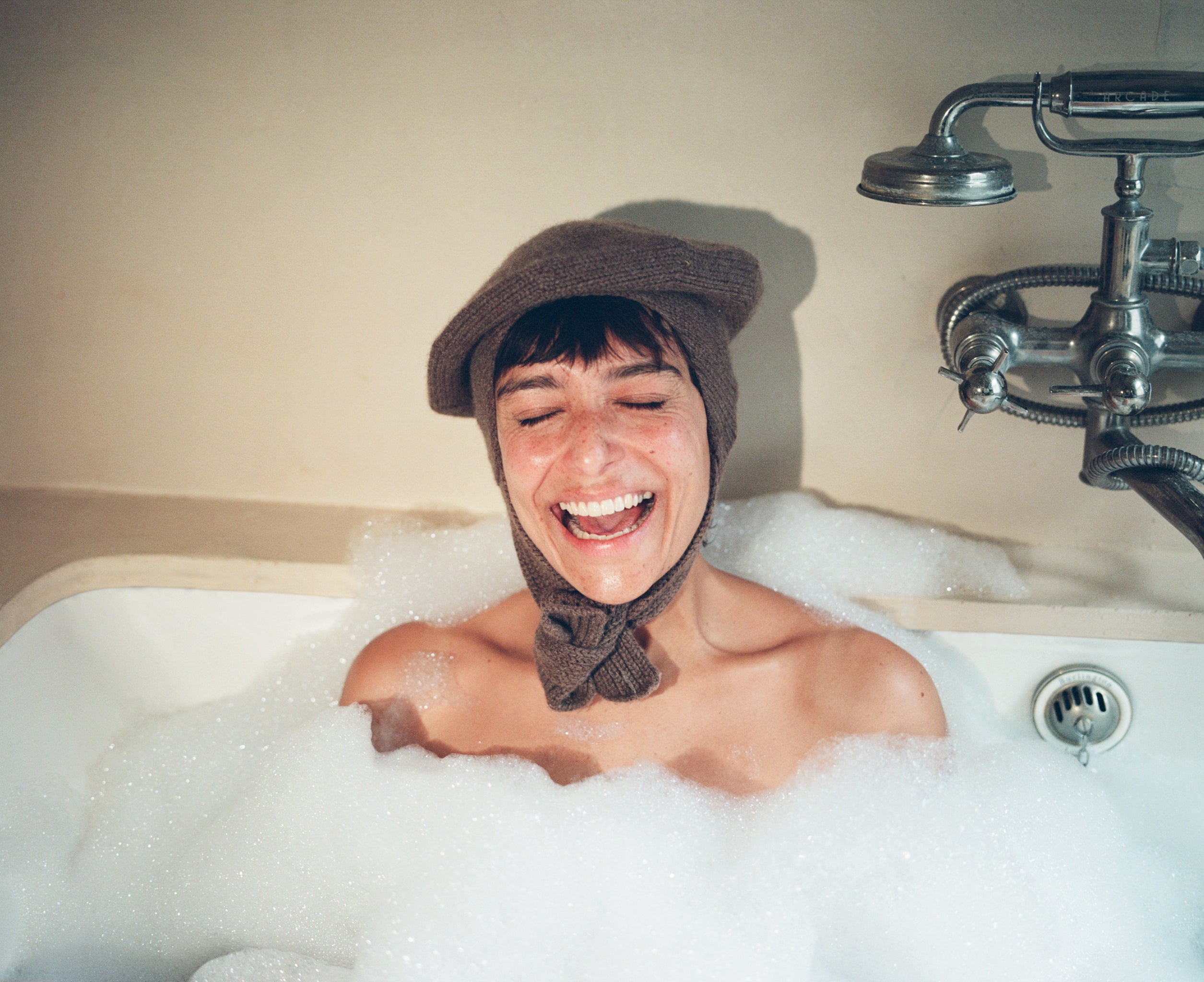 Model  in a bubble bath wearing the classic hat in 100% cashmere in camel