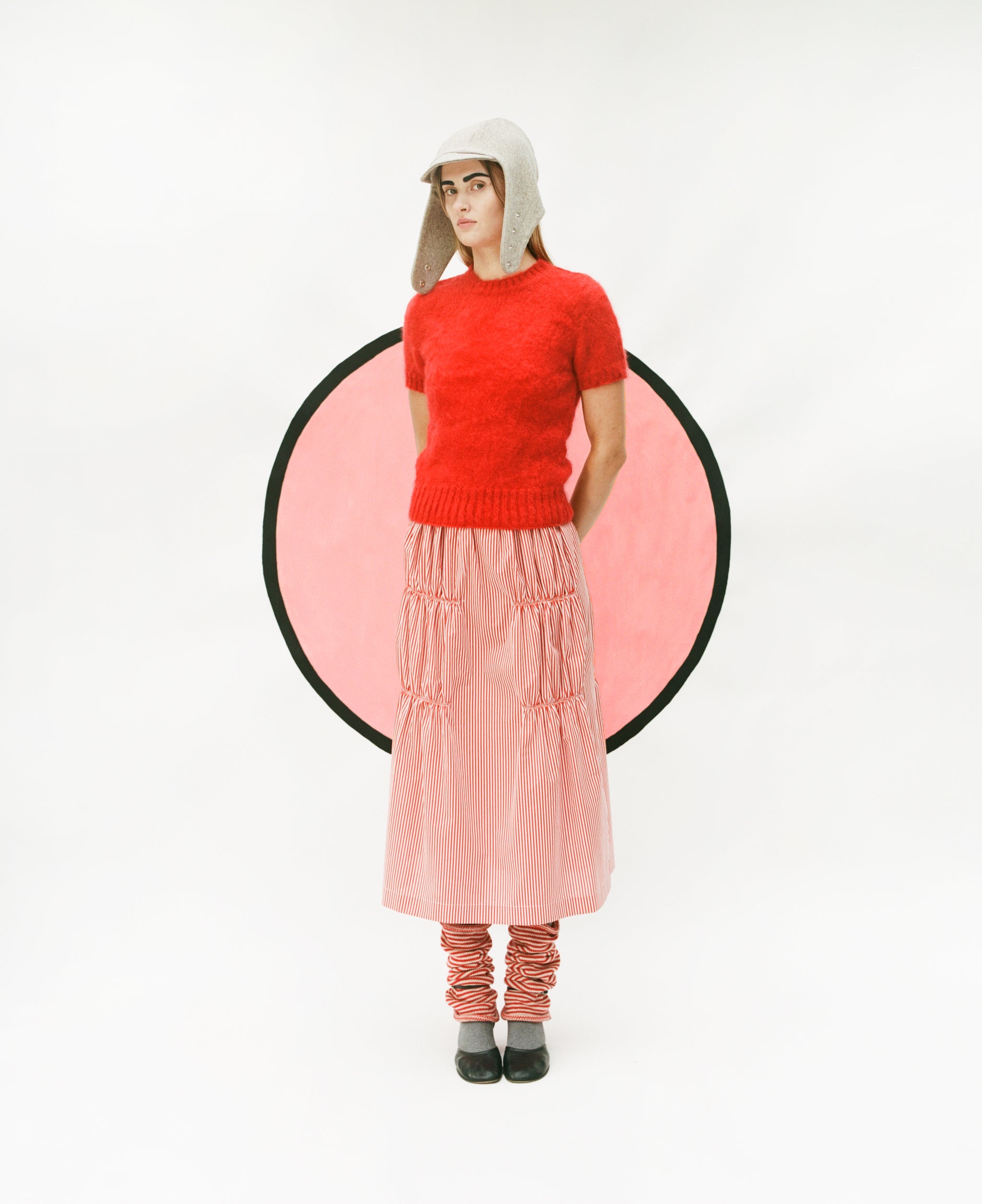 Model wearing Flying Hat, T-shirt sweater in red, ruche cotton skirt in red & white and stripy leg warmers in red & oatmeal
