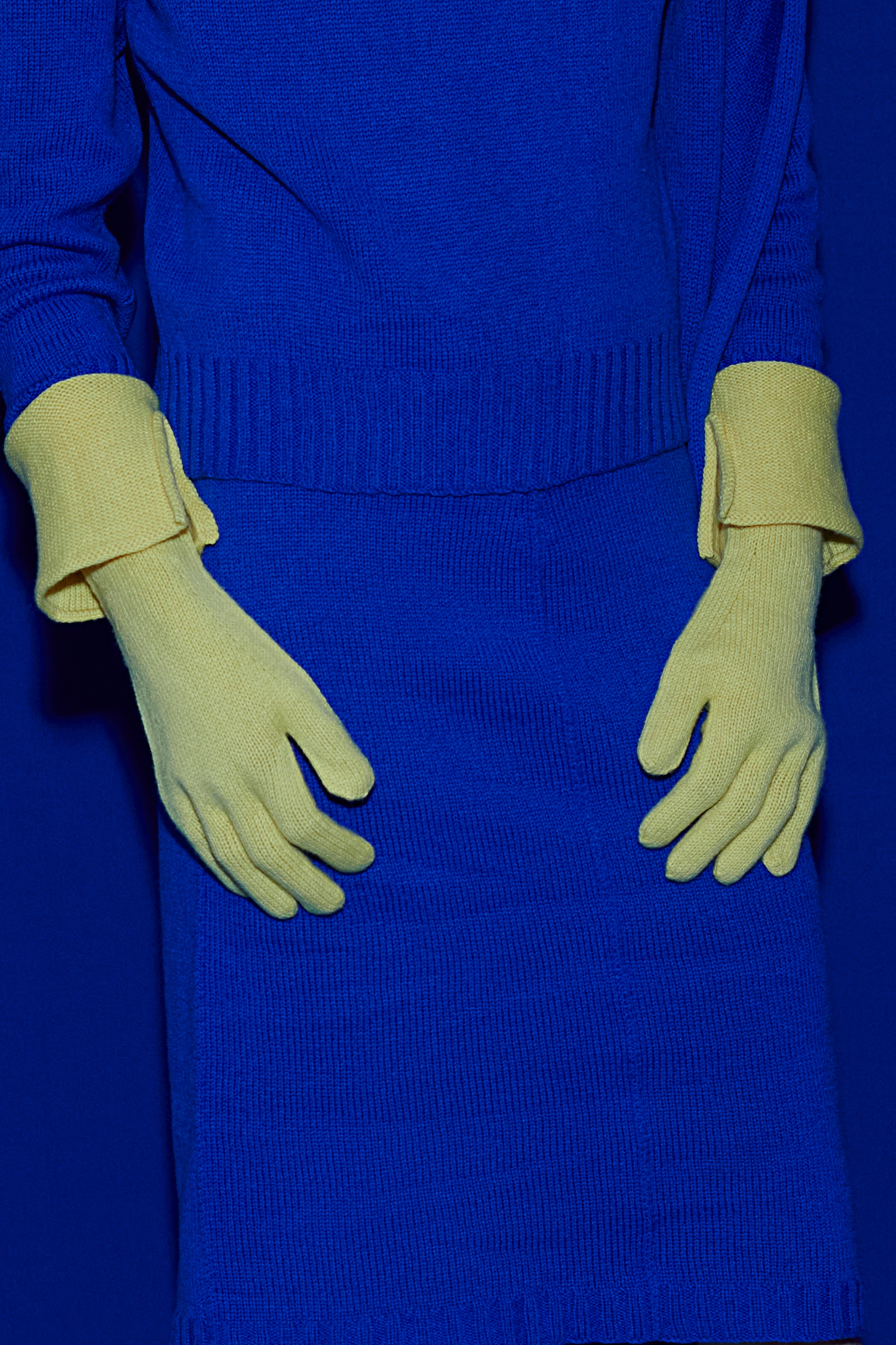 Full knit outfit: matching blue top and skirt and yellow gloves with a matching blue background
