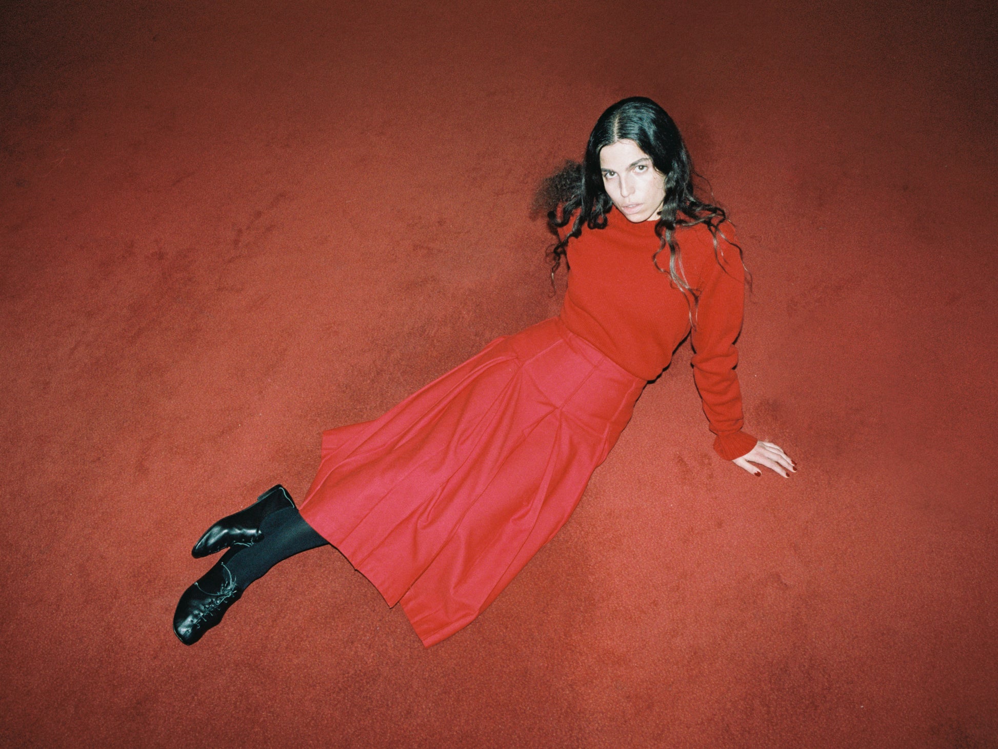 model wearing traditional sweater in red with red pleat skirt