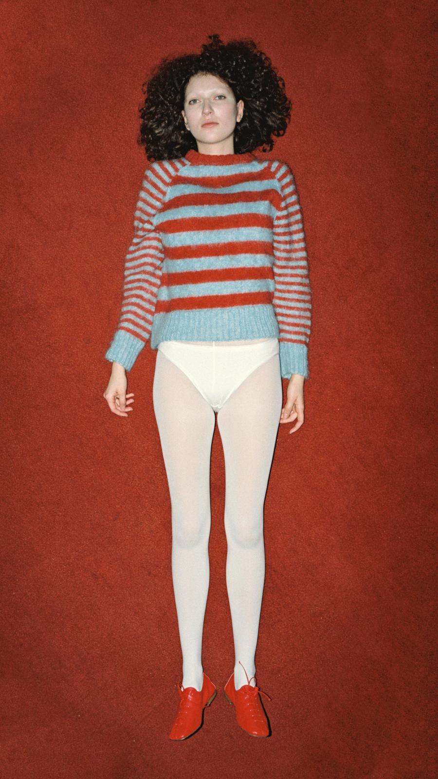 Look 15 - Model wearing Mohair Stripe Raglan in baby blue & dark orange with white tights and red flat lace up shoes