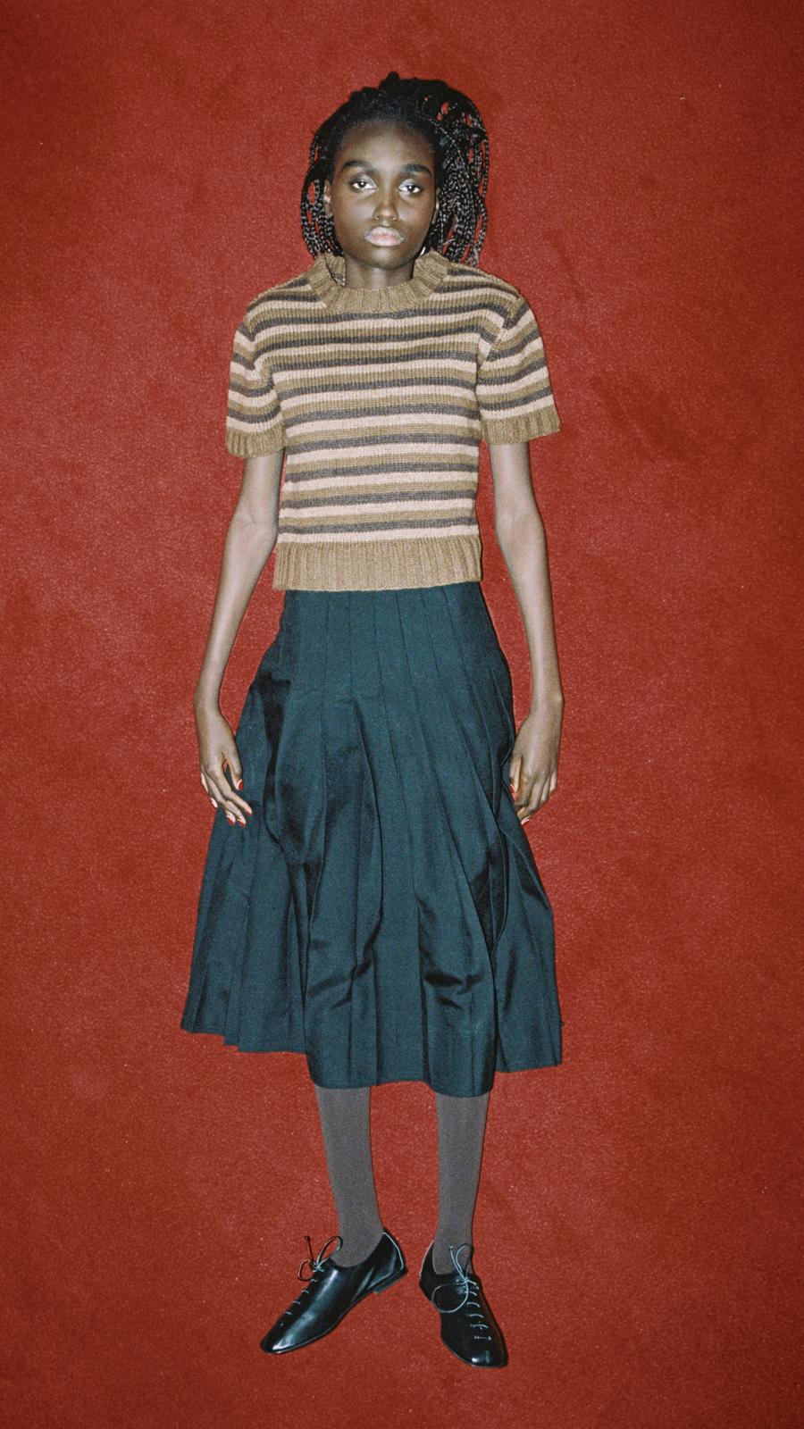 Look 11 - Model wearing t-shirt sweater in spaniel and chocolate brown stripes, Ankle Pleat Skirt in black and black flat lace up shoes
